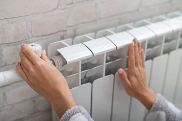 Närbild av en kvinnlig hand som reglerar temperaturen på en värmeelement — Stockfoto