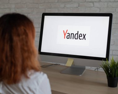 16 Eylül 2020, Rusya, Novosibirsk: Ekranda Yandex logosu olan bir kadının bilgisayarın başında oturması.