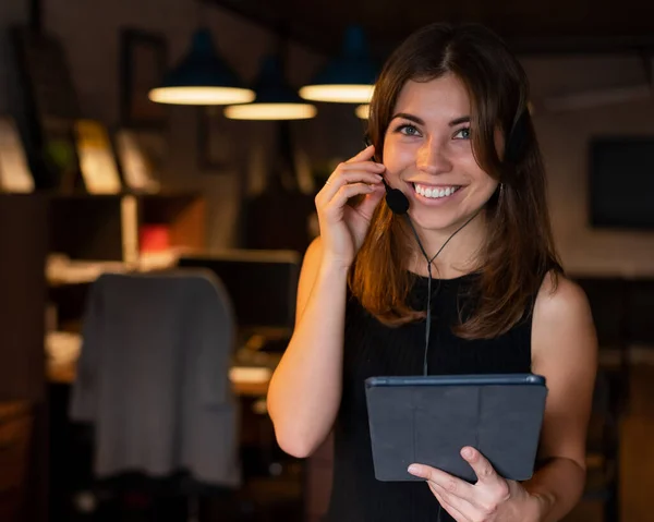 헤드폰을 쓰고 있는 아름다운 비지니스 여성이 사무실에서 디지털 태블릿을 들고 있습니다. — 스톡 사진