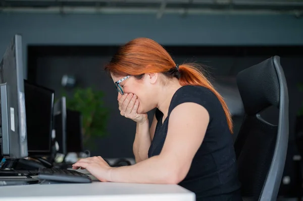 En kvinna är sjuk och nyser vid skrivbordet på kontoret — Stockfoto
