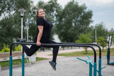 Düz olmayan barlarda egzersiz yapan tombul genç bir kadın. Beyaz kız şınav çekiyor.