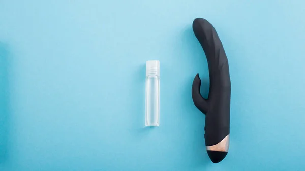 Vista superior de un vibrador vaginal negro del clítoris y un tubo de lubricante sobre un fondo azul — Foto de Stock