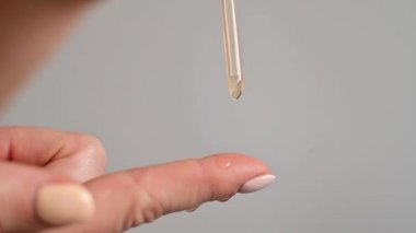 Yakın plan kadın beyaz arka plan üzerinden parmağına yağ damlatıyor.