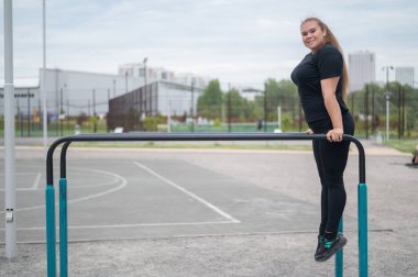 Düz olmayan barlarda egzersiz yapan tombul genç bir kadın. Beyaz kız şınav çekiyor.