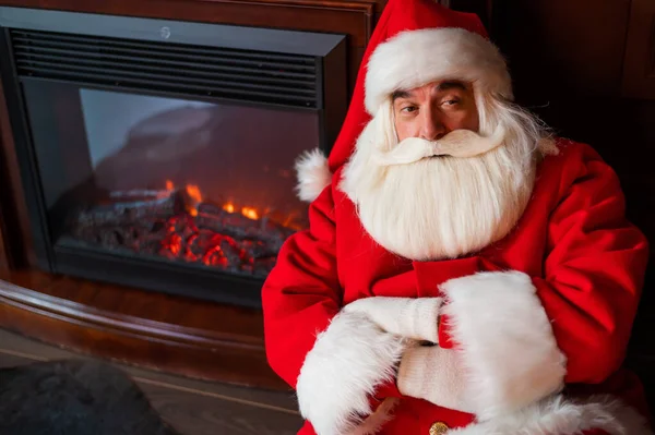 Der Weihnachtsmann sitzt an Heiligabend am Kamin — Stockfoto