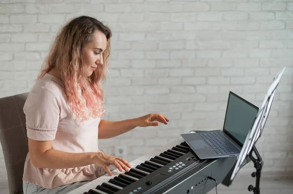 Musik Online-Lernkonzept. Eine Frau leitet Fernunterricht zum Klavierspielen per Videoübertragung auf einem Laptop — Stockfoto