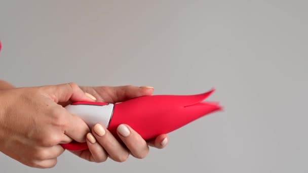 En kvinna håller en klitorisk vibrator i form av en röd tulpan. Sexleksaker med snygg modern design — Stockvideo