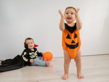  Tatlı çocuklar cadılar bayramını beyaz arka planda kutluyor. Dracula kostümü ve balkabağı giymiş iki çocuk.