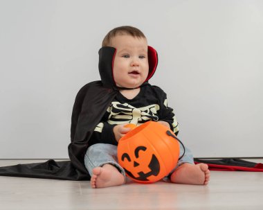 Beyaz arka planda şeker sepeti tutan Dracula Cadılar Bayramı kostümlü beyaz tatlı çocuk.