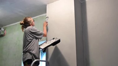 Kafkas kadın silindirle duvar boyuyor.