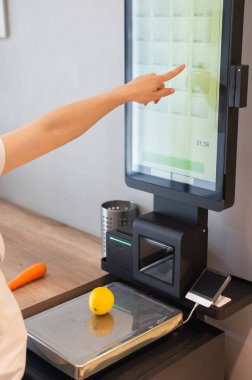 Kendini kontrol eden bir kadın limon tartıyor.