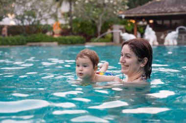 Beyaz kadın tatilde havuzda yüzerken oğlunu kucağına aldı