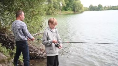Baba ve oğul nehirde balık tutuyor.