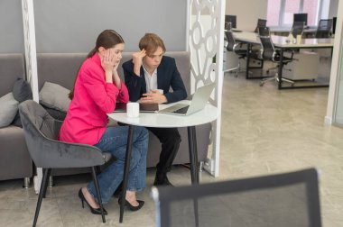 Meslektaşlar dizüstü bilgisayarda oturup iş konuşuyorlar.