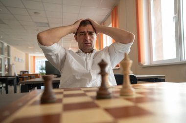 Orta yaşlı beyaz adam satranç oynuyor.