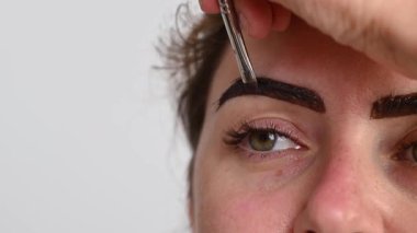 Beyaz kadın kaş boyama prosedürü uyguluyor.