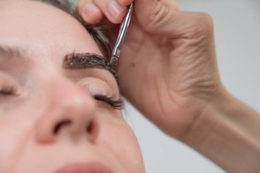 Beyaz kadın kaş boyama prosedürü uyguluyor.