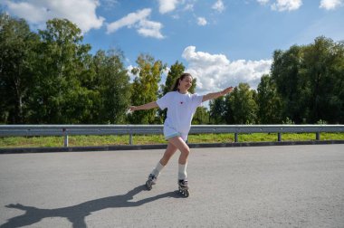 Beyaz kadın yolda hızla paten kayıyor.