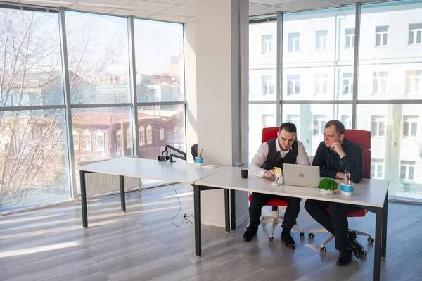 İki beyaz adam bir masada oturup iş tartışıyorlar.