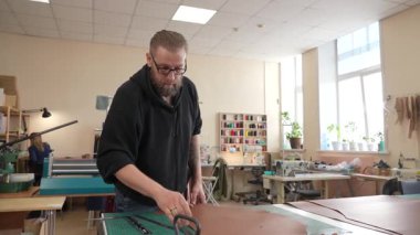 Beyaz sakallı adam bir atölyede bronzlaştırıcı olarak çalışıyor.