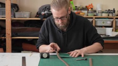 Beyaz sakallı adam bir atölyede bronzlaştırıcı olarak çalışıyor.