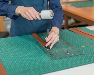 Kadın bronzlaştırıcı bir atölyede deri kemerin kenarlarını inceliyor.