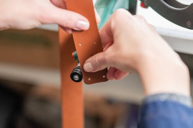 Deri işçisi atölyede kemer için deri şeritlerini öğütüyor.