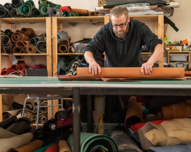 Beyaz sakallı adam bir atölyede bronzlaştırıcı olarak çalışıyor.