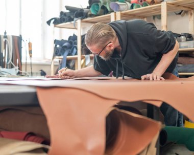 Beyaz sakallı adam bir atölyede bronzlaştırıcı olarak çalışıyor.