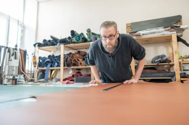 Beyaz sakallı adam bir atölyede bronzlaştırıcı olarak çalışıyor.