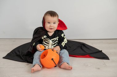 Beyaz arka planda şeker sepeti tutan Dracula Cadılar Bayramı kostümlü beyaz tatlı çocuk.