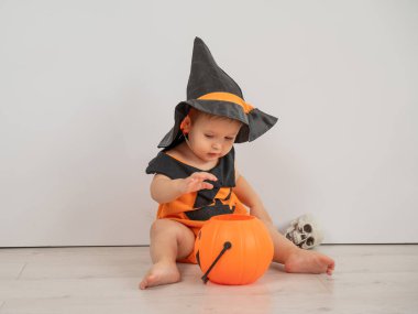 Cadılar bayramı balkabağı kostümlü beyaz arka planda şeker sepeti tutan yakışıklı beyaz çocuk.