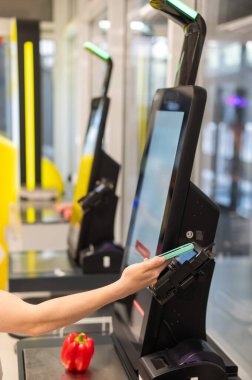 Bir kadın kendini kontrol ederken akıllı telefonuyla ödeme yapar.