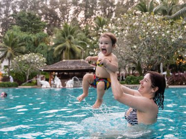 Beyaz kadın tatilde havuzda yüzerken oğlunu kucağına aldı