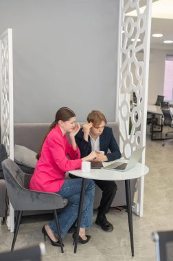 Meslektaşlar dizüstü bilgisayarda oturup iş konuşuyorlar.