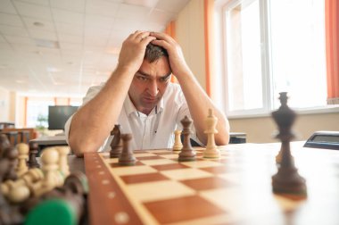 Orta yaşlı beyaz adam satranç oynuyor.