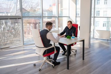 İki beyaz adam bir iş toplantısında iletişim kuruyor.