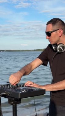 Beyaz adam plajda DJ olarak çalışıyor.