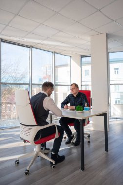 İki beyaz adam bir iş toplantısında iletişim kuruyor.