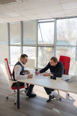 Bir ofiste pazarlık yapan iki beyaz adam.