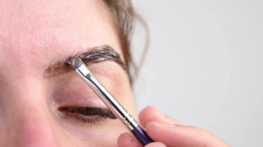 Beyaz kadın kaş boyama prosedürü uyguluyor.