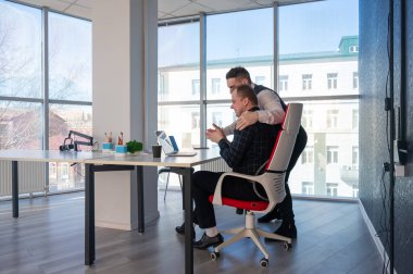 Beyaz adam çalışma masasında durmuş iş hakkında konuşuyor.