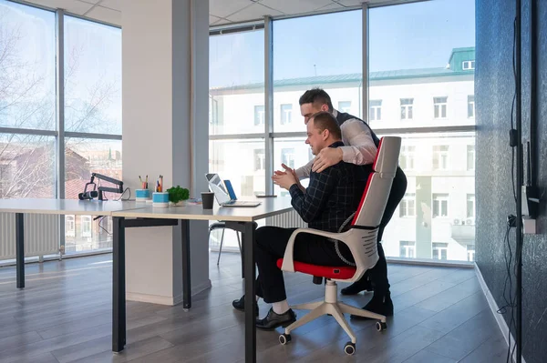 Beyaz adam çalışma masasında durmuş iş hakkında konuşuyor.