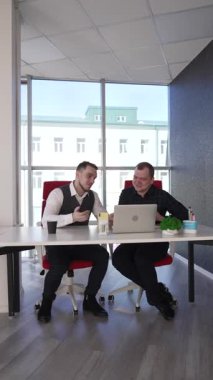 İki beyaz adam bir masada oturup iş tartışıyorlar.