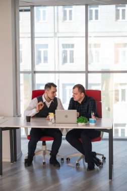 İki beyaz adam bir masada oturup iş tartışıyorlar.