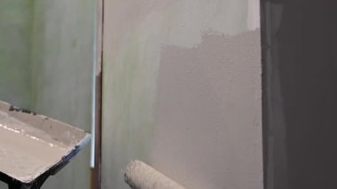 Kafkas kadın silindirle duvar boyuyor.