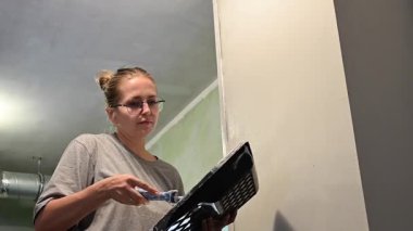 Kafkas kadın silindirle duvar boyuyor.