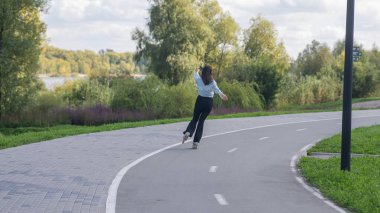 Beyaz kadın parkta paten kayıyor.