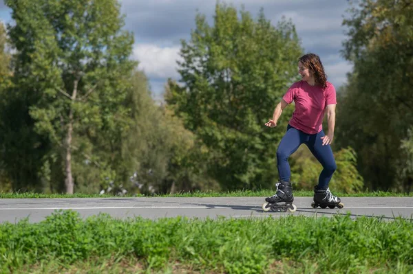 Beyaz kadın parkta paten kayıyor.