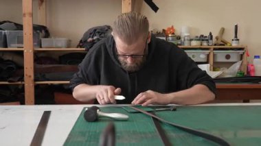 Beyaz sakallı adam bir atölyede bronzlaştırıcı olarak çalışıyor.